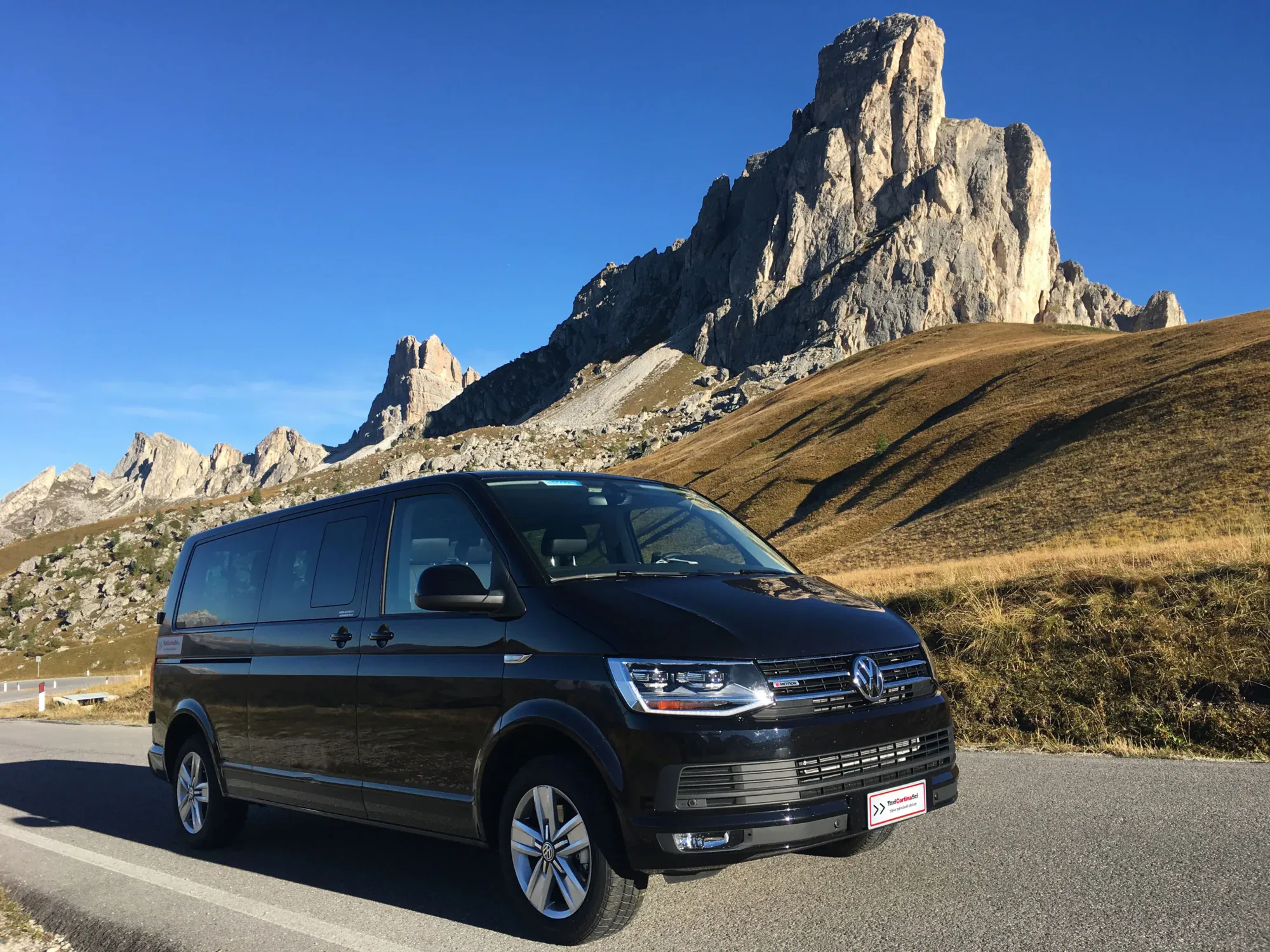 Minivan nero al Passo Giau con il monte Ra Gusela sullo sfondo